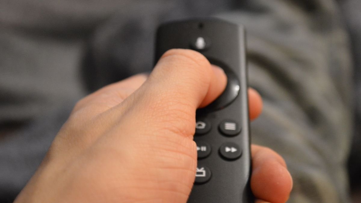 Hand mit Tasten auf einer Fernbedienung