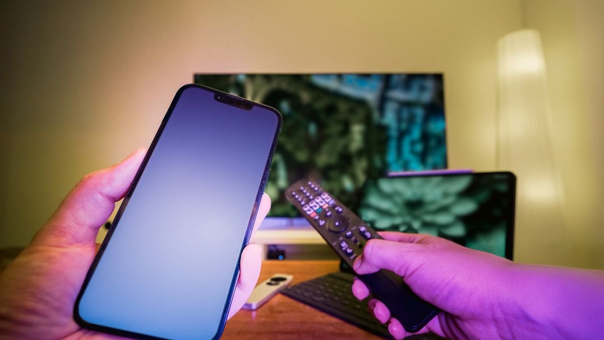 Telefon und Fernbedienung vor einem angeschlossenen Fernseher